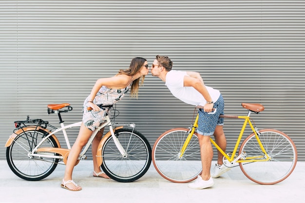 Foto vista lateral de um casal com bicicletas a beijar-se ao ar livre