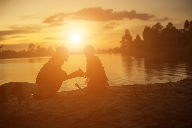 Vista lateral de um casal na praia contra o céu durante o pôr do sol