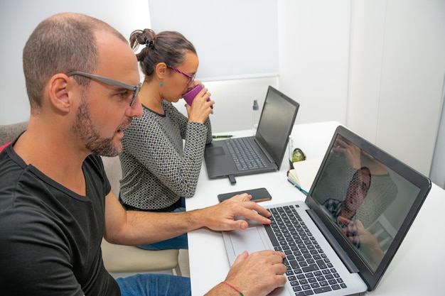 Foto vista lateral de um casal trabalhando em laptops em casa