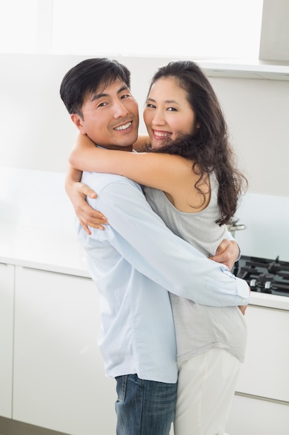 Vista lateral de um homem abraçando mulher na cozinha