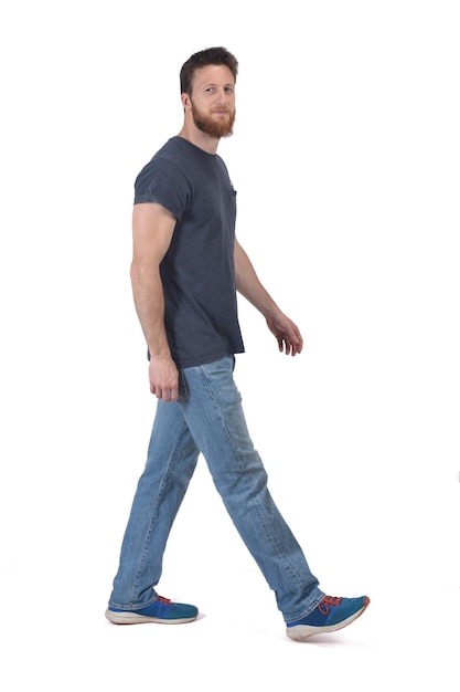 Vista lateral de um homem andando e olhando para a câmera no fundo branco