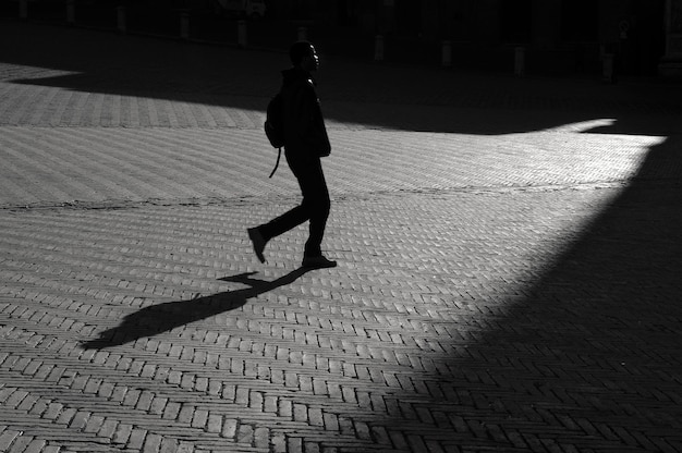 Vista lateral de um homem caminhando em uma rua de paralelepípedos
