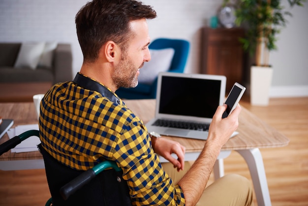 Vista lateral de um homem com deficiência usando o telefone no trabalho