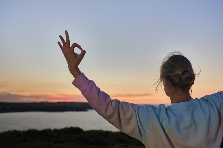 Foto vista lateral de um homem com os braços levantados contra o céu durante o pôr do sol