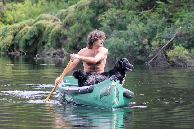 Vista lateral de um homem com um cão no lago