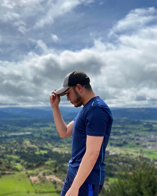 Foto vista lateral de um homem fotografando enquanto está de pé no campo contra o céu