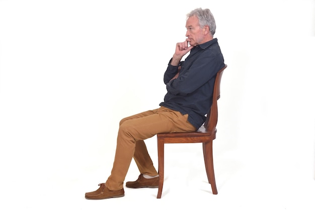 Vista lateral de um homem pensativo sentado em uma cadeira no fundo branco