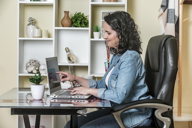 Foto vista lateral de um homem usando um telefone móvel enquanto está sentado em uma mesa