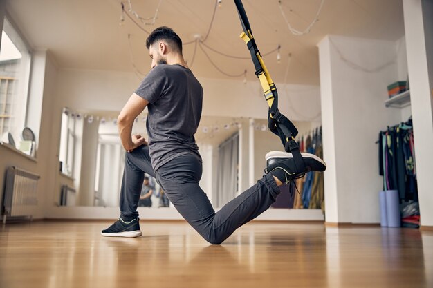 Vista lateral de um jovem em forma realizando um exercício de força em uma academia de ginástica