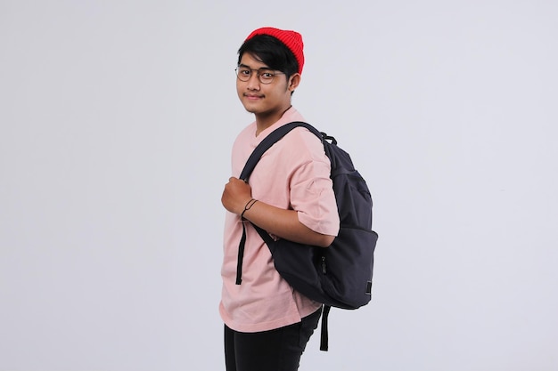 Vista lateral de um jovem estudante asiático carregando uma mochila