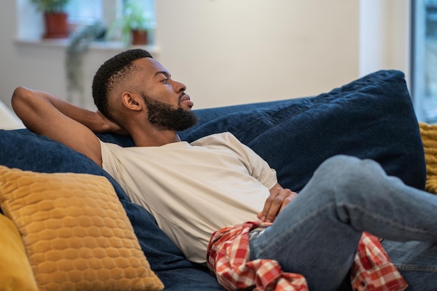 Foto vista lateral de um jovem sentado no sofá em casa