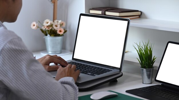 Vista lateral de um jovem trabalhando com vários dispositivos eletrônicos