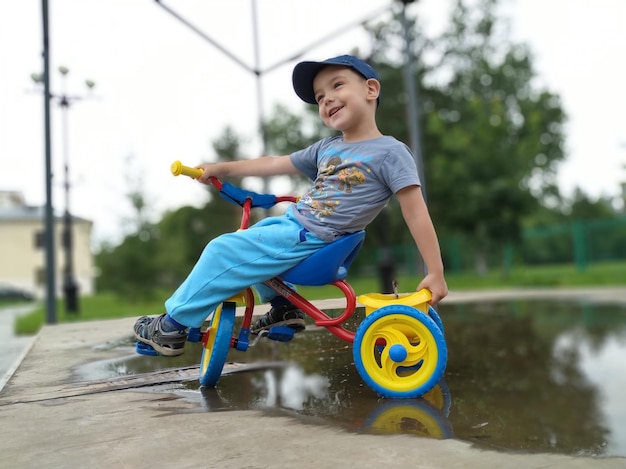 Foto vista lateral de um menino andando de bicicleta em uma poça molhada