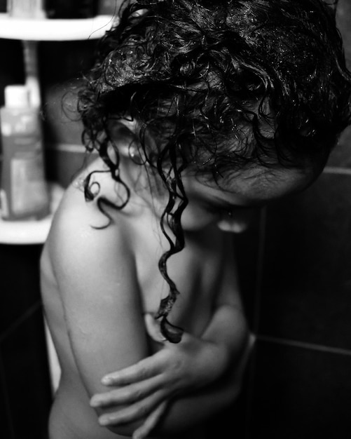 Foto vista lateral de uma garota nua com cabelos encaracolados de pé com os braços cruzados