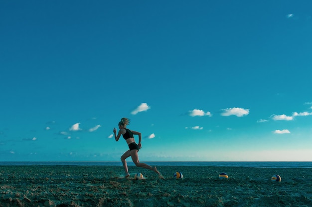 Vista lateral de uma jovem correndo enquanto se exercita na praia contra o céu azul