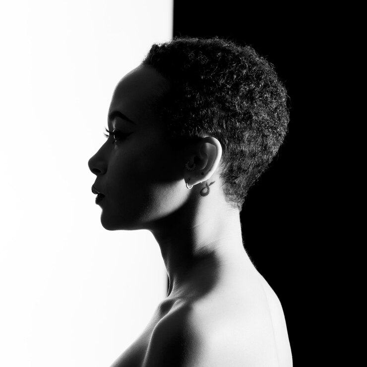 Foto vista lateral de uma jovem em topless contra um fundo preto e branco