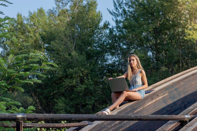 Vista lateral de uma jovem que trabalha como trabalhadora on-line remota em ambiente natural no horário de verão