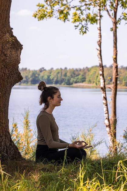 Foto vista lateral de uma jovem sentada ao lado do lago