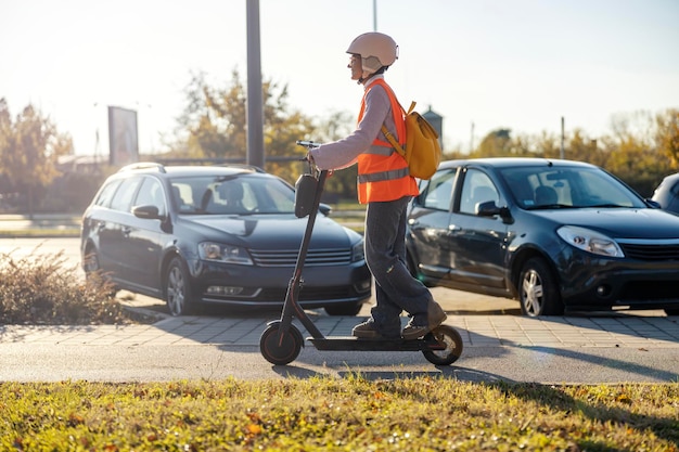 Foto vista lateral de uma menina dirigindo uma scooter elétrica na rua