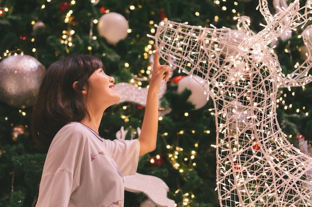 Foto vista lateral de uma menina sorridente olhando para a decoração de natal iluminada em casa