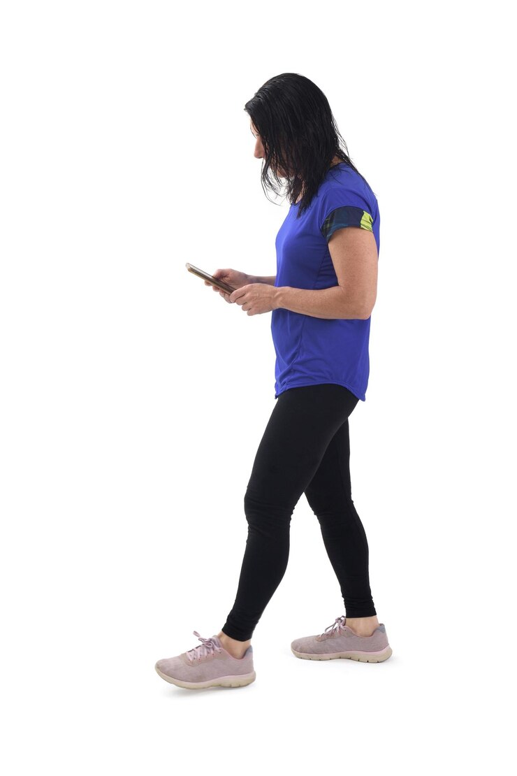 Foto vista lateral de uma mulher a andar a olhar para o seu telemóvel em fundo branco
