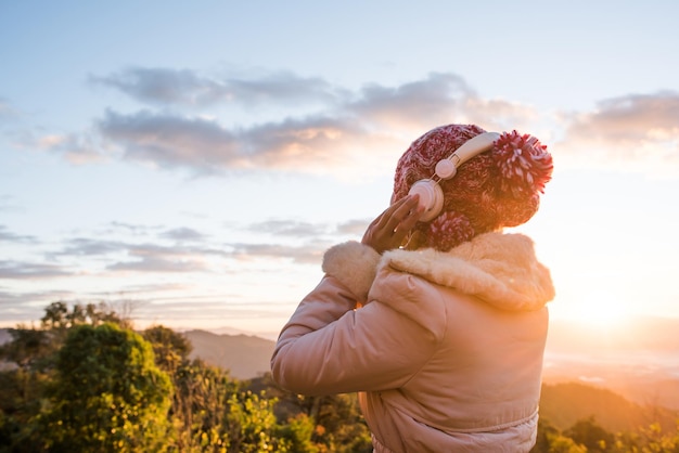 Foto vista lateral de uma mulher com roupas quentes de pé contra o céu durante o pôr do sol