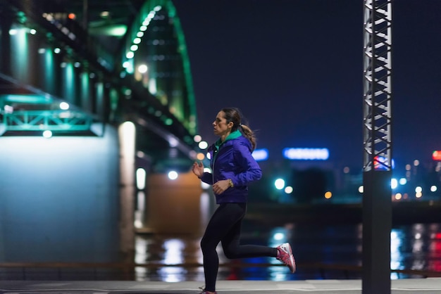 Foto vista lateral de uma mulher correndo pelo rio à noite