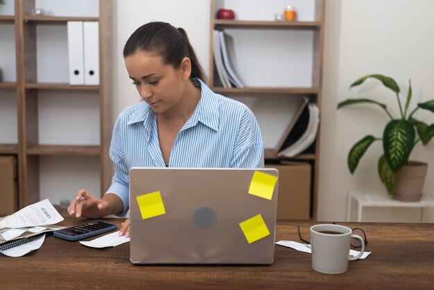 Foto vista lateral de uma mulher de negócios usando um laptop enquanto está sentada na mesa