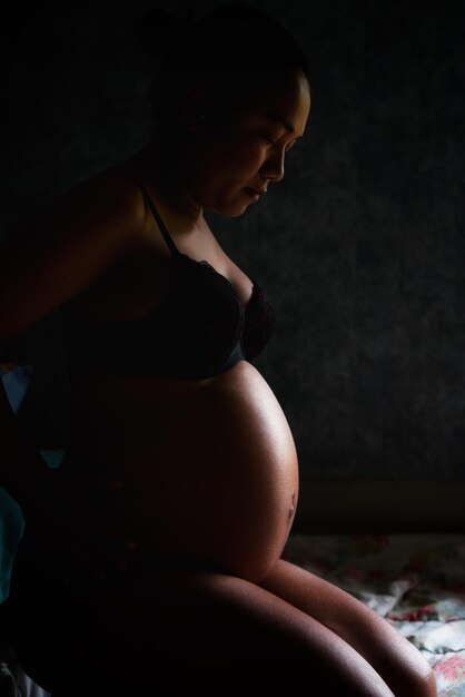 Foto vista lateral de uma mulher grávida sentada em casa