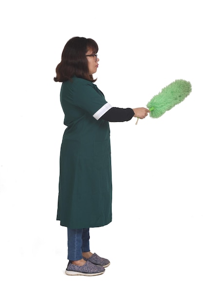 Vista lateral de uma mulher latina limpando o pó com um espanador no fundo branco