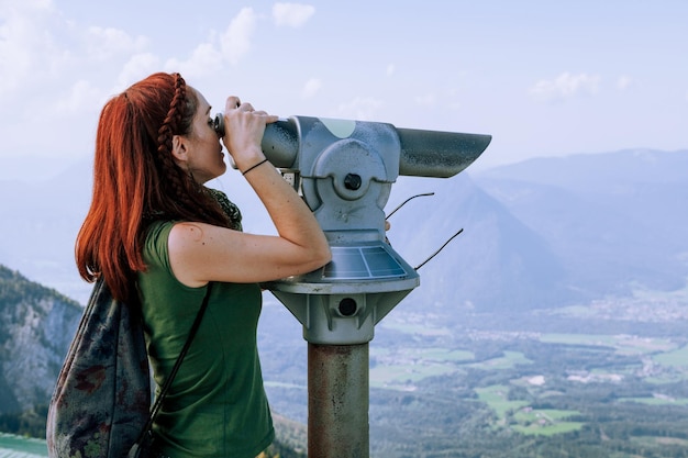 Vista lateral de uma mulher olhando através de um telescópio enquanto está de pé contra o céu