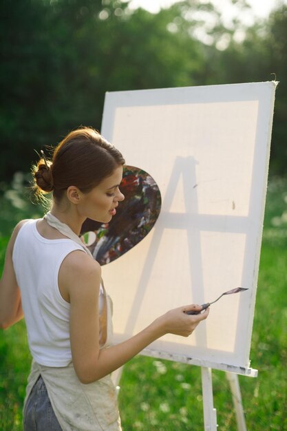 Foto vista lateral de uma mulher segurando um livro enquanto está de pé ao ar livre