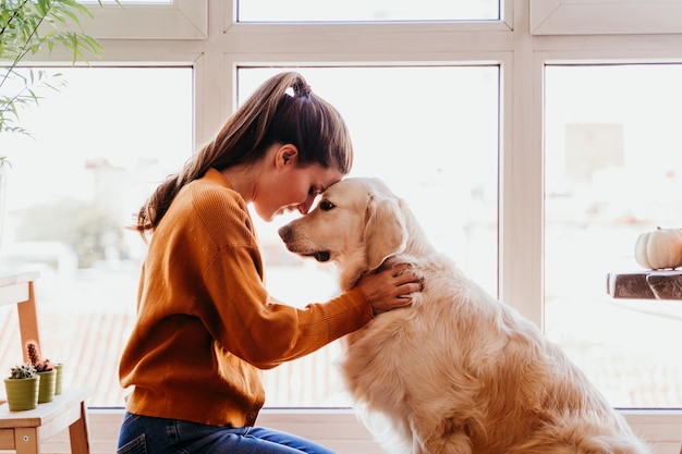 Foto vista lateral de uma mulher sorridente segurando um cachorro em casa