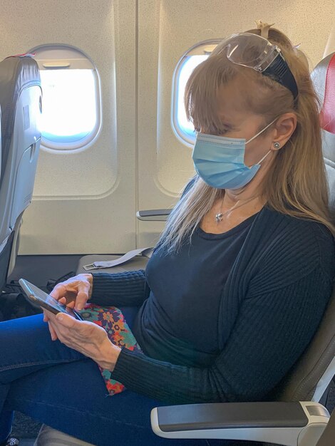 Vista lateral de uma mulher usando máscara sentada em um avião