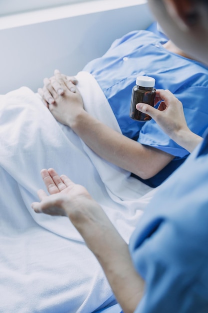 Vista lateral de diversos médicos que examinan a una paciente asiática en la cama en la sala del hospital