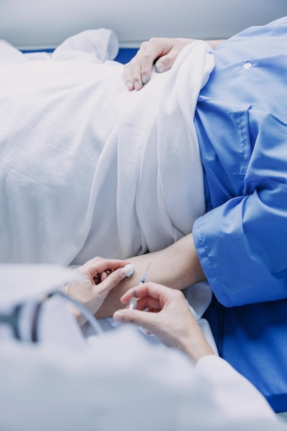 Vista lateral de diversos médicos que examinan a una paciente asiática en la cama en la sala del hospital