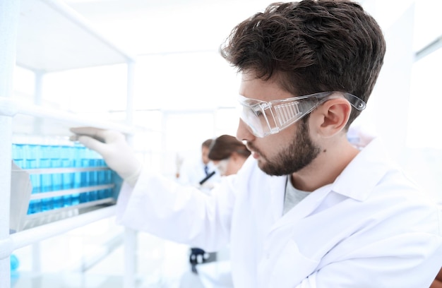 Vista lateral do cientista focado segurando o tubo de ensaio em laboratório