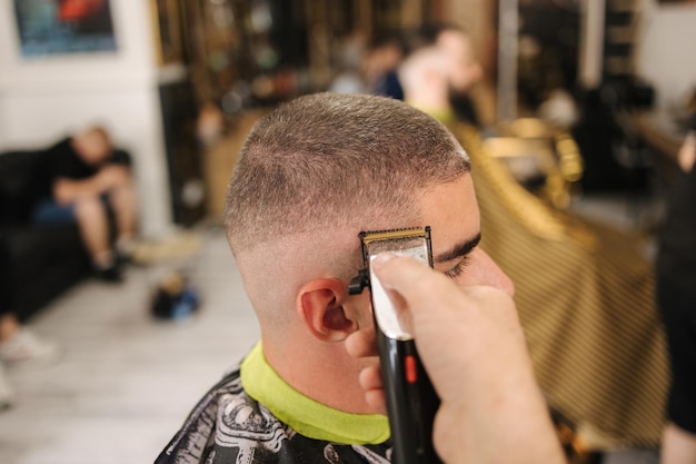 Vista lateral do cliente masculino sentado na barbearia corte de cabelo no salão