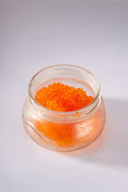 Vista lateral do frasco de vidro fechado com caviar vermelho de salmão rosa isolado no fundo branco