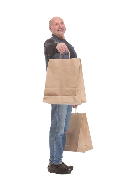 Vista lateral do homem amadurecido feliz carregando sacolas de compras