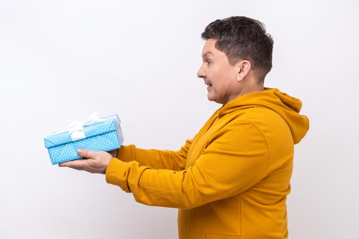 Foto vista lateral do homem generoso positivo sorrindo e dando caixa de presente compartilhando presente de feriado