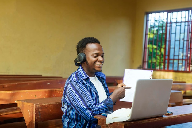 Vista lateral do jovem estudante negro africano usando laptop para e-learning