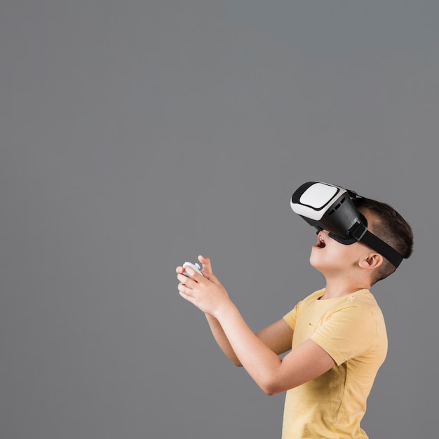 Foto vista lateral do menino espantado, experimentando a realidade virtual