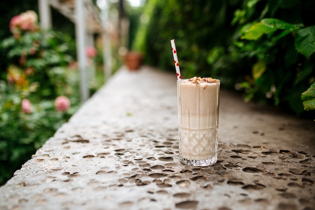 Vista lateral do milkshake de chocolate com canudo na pedra