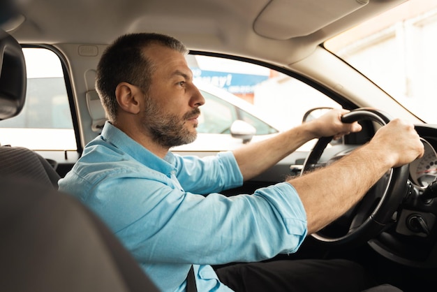 Foto vista lateral do motorista do sexo masculino dirigindo o carro sentado dentro do automóvel