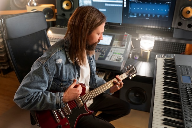 Foto vista lateral do músico masculino tocando instrumentos no estúdio