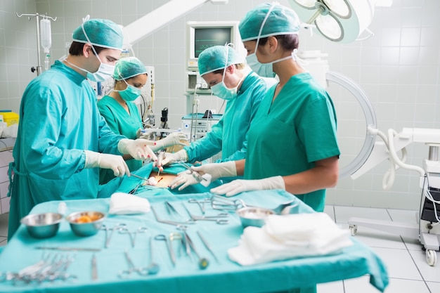 Vista lateral de un equipo quirúrgico que opera a un paciente