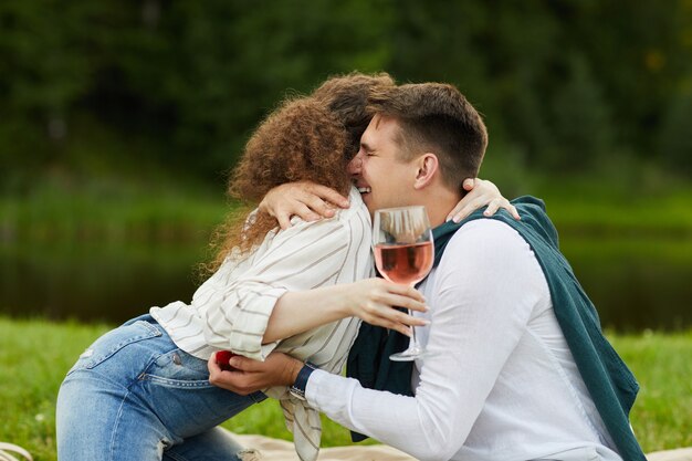 Foto vista lateral de la feliz joven abrazando a su novio mientras acepta la propuesta de matrimonio durante la cita romántica al aire libre