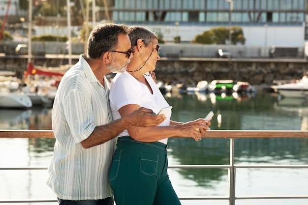 Vista lateral de la feliz pareja madura abrazándose en el muelle de la marina