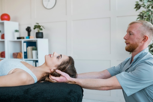 Vista lateral del fisioterapeuta realizando ejercicios en paciente femenina